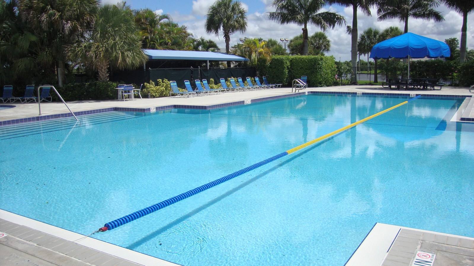 Rose G. Price Park swimming pool with blue water, trees, and surrounding facilities in Pembroke Pines, Florida